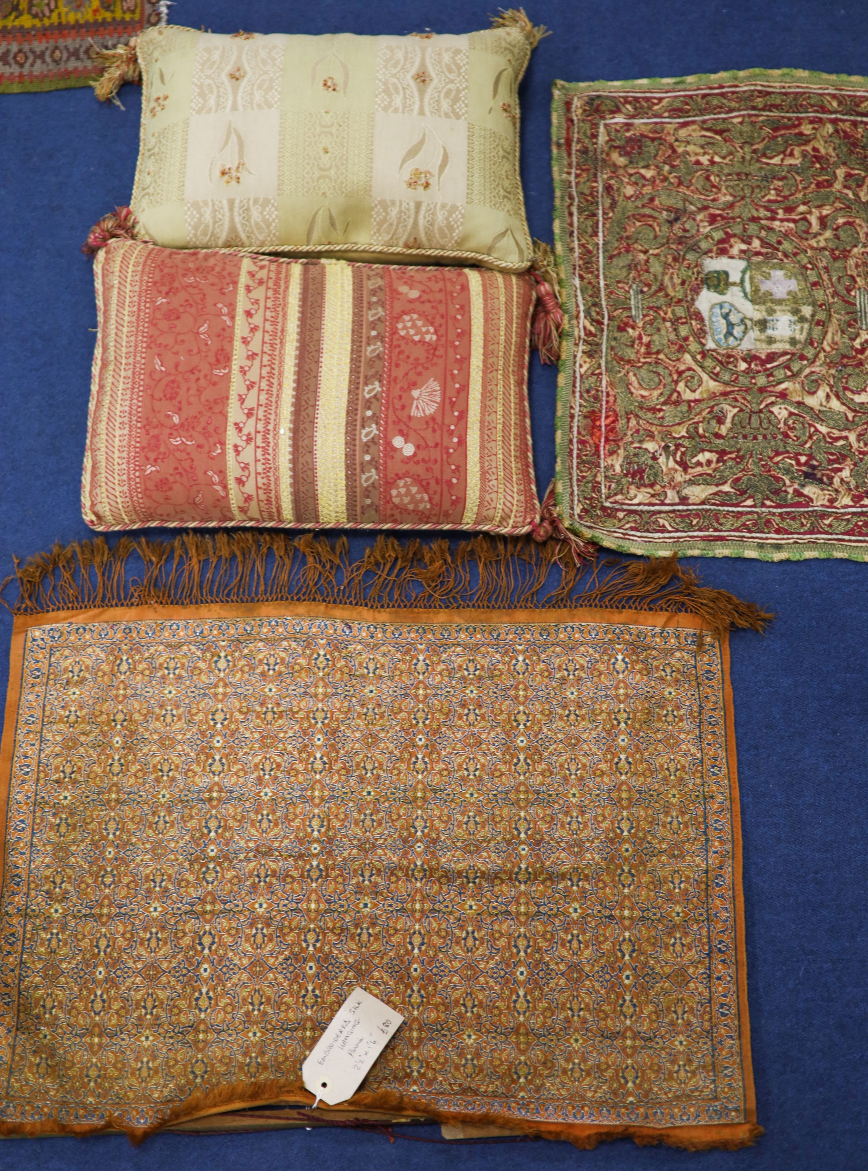 A Turkish / Persian embroidered silk panel with central armorial, 53 x 38cm. an embroidered silk hanging, 45 x 65cm and two cushions, 40 x 27cm.